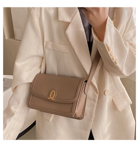 Brown leather crossbody bag with gold metal buckle shown on model in mirror selfie
