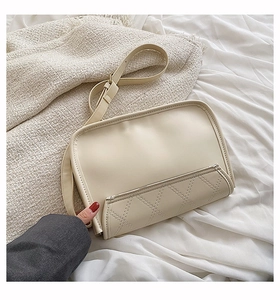 Detail of cream white crossbody bag featuring quilted lattice pocket and gold hardware