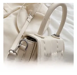 Detail view of cream handbag with heart embossing and silver chain strap