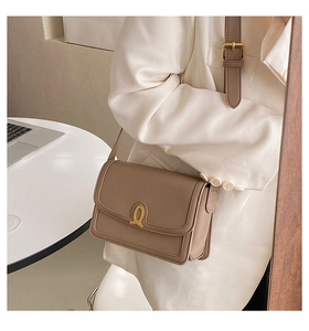 Detail of khaki leather crossbody bag with vintage gold metal knot clasp and adjustable strap