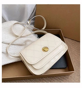 Detail of cream white quilted crossbody bag with golden rotary lock in gift box