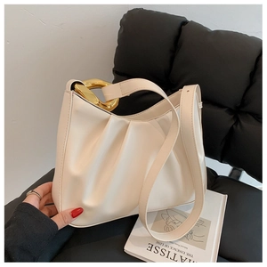 Close-up of cream pleated cloud bucket bag featuring a chunky gold chain strap