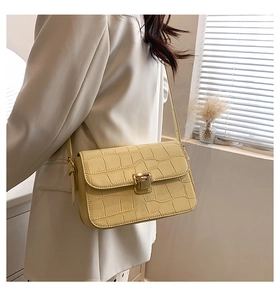 Lifestyle view of cream crocodile embossed crossbody bag with gold metal buckle