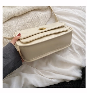 Detail view of cream leather crossbody bag featuring quilted patterns and gold twist lock