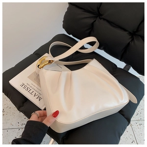 Detail of creamy white ruched bucket bag with polished gold metal rings on a leather seat