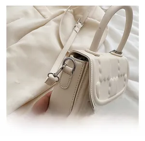 Detail of premium silver metal hooks and heart pattern texture on beige square bag