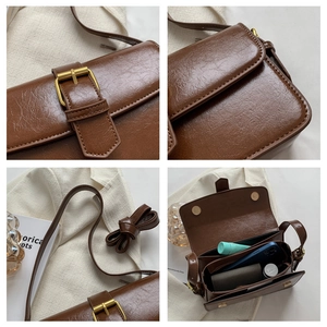 Detail view of brown vintage satchel showing pebbled leather texture and gold buckle