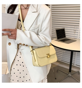 Close-up of yellow crocodile pattern handbag with elegant gold metal lock and leather texture