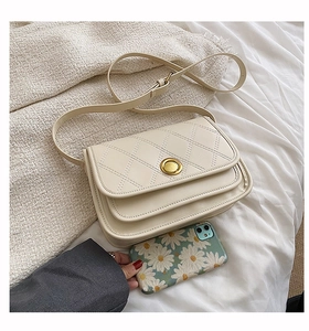 Detail of beige quilted crossbody bag with golden twist lock and accordion side structure