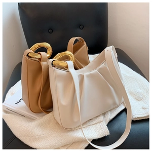 Detail of minimalist pleated cloud bags with polished gold metal hardware accents