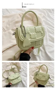 Macro view of mint green handbag with cloud-embossed texture and heart chain detail