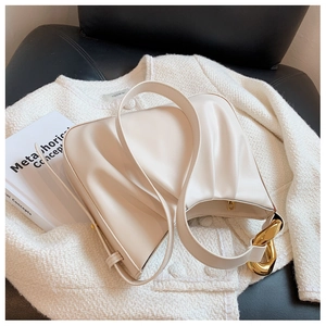 Detail view of beige ruched cloud bucket bag with large decorative golden chain link buckle