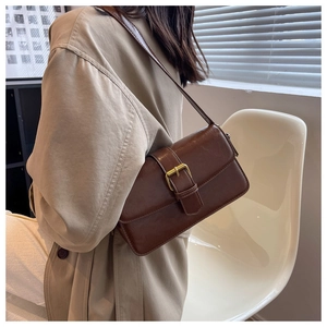Detail of dark brown vintage rectangle shoulder bag with a gold buckle closure