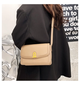 Detail view of a beige square leather crossbody bag with a distinctive yellow buckle