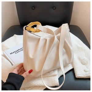 Detail of cream pleated cloud bag with matte leather finish and gold chain metal buckle