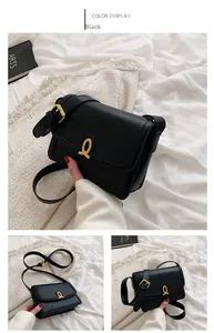 Detail of a matte black shoulder bag featuring a gold horseshoe twist lock and adjustable strap