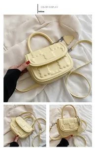 Detail of yellow PU leather handbag with 3D floral texture and heart charm