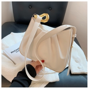 Detail of white leather ruched bag with a stylish large golden horseshoe metal buckle
