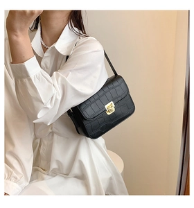 Detail of black crocodile texture shoulder bag with elegant golden square metal clasp