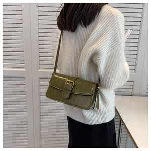Detail of olive green baguette bag with glossy wrinkled texture and gold metal buckle