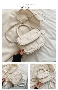 Detail of white PU leather crossbody bag featuring embossed bear patterns and chain charm