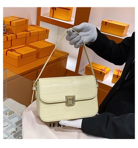 Detailed macro view of beige crocodile embossed PU leather bag with golden metal buckle