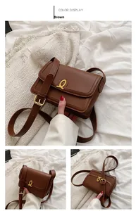 Detail of a brown leather shoulder bag featuring a gold equestrian-style buckle and strap