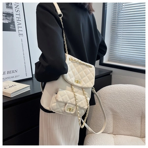 Detail view of beige quilted backpack with gold chain straps on a model's back