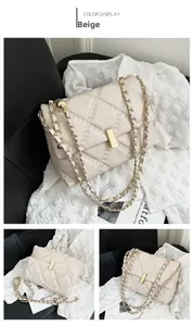 Dettaglio borsa trapuntata beige con tracolla a catena dorata e chiusura in metallo