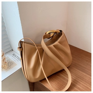 Detail of camel ruched bucket bag with large gold metallic buckle and fine PU leather texture
