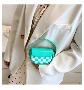 Détail du mini sac selle vert menthe avec damier porté avec un blazer blanc élégant