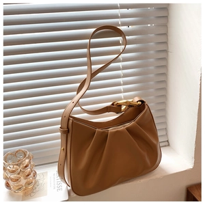 Close-up of tan ruched cloud bag featuring an elegant gold irregular metal buckle detail