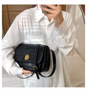 Classic black quilted crossbody bag with gold oval twist lock shown on a model