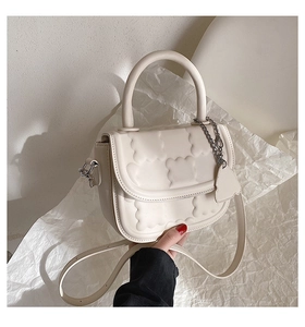 Close-up of a cream white mini crossbody bag featuring a unique 3D cloud-shaped embossed pattern