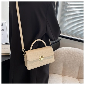Dettaglio borsa a mano beige stampa coccodrillo con finiture dorate e manico superiore