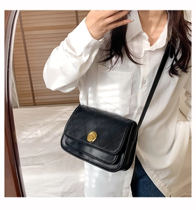 Mirror selfie showing a black quilted leather crossbody bag with a gold buckle on the front