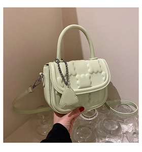 Close-up of light green hand-held bag with wavy relief texture and metal chain