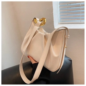 Detail of a creamy white pleated cloud bag featuring an elegant gold heart-shaped metal buckle