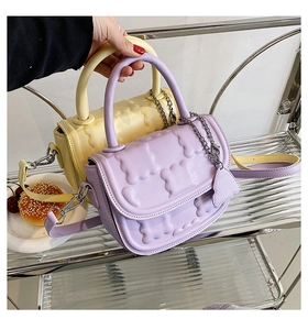 Close-up of quilted macaron-colored crossbody bags with cute bear charm and chain detail