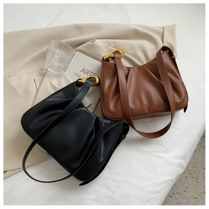 Detail of ruched cloud bucket bags with oversized gold chain hardware and PU leather texture