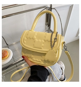 Detail of yellow crossbody bag featuring cloud-like embossed patterns and silver hardware