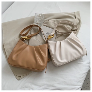 Close-up of pleated leather texture and gold metal chain hardware on fashion hobo bags