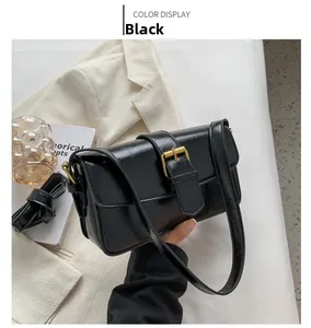 Close-up of black glossy patent leather shoulder bag with a gold metal buckle detail