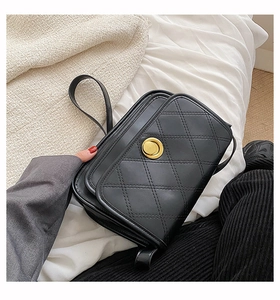 Detail of black quilted shoulder bag with gold metal twist lock and faux leather texture