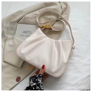 Detail of off-white pleated cloud bag with gold chain buckle on beige aesthetic background