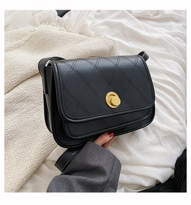 Detail of black quilted crossbody bag featuring a golden circular twist lock closure