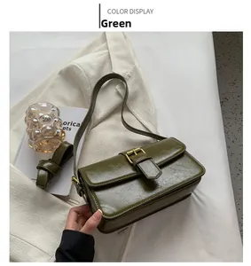 Macro shot of olive green wrinkled leather handbag with gold buckle on beige blazer