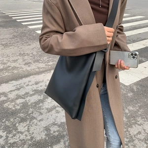 Minimalist black large capacity tote bag styled with brown coat for daily commuting