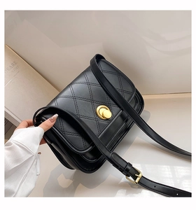 Detail of a black quilted crossbody bag featuring a gold circular twist lock and leather strap