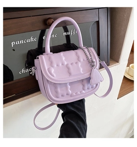 Detail of light purple waffle-textured crossbody bag with decorative biscuit charm